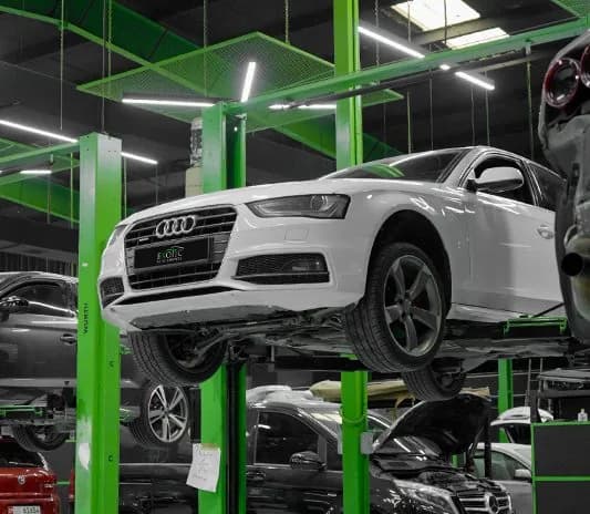White Audi on the lift for an underbody inspection at the Exotic Auto Services workshop