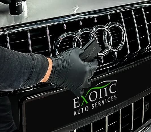 Technician working on the front grille of an Audi at the Exotic Auto Services workshop