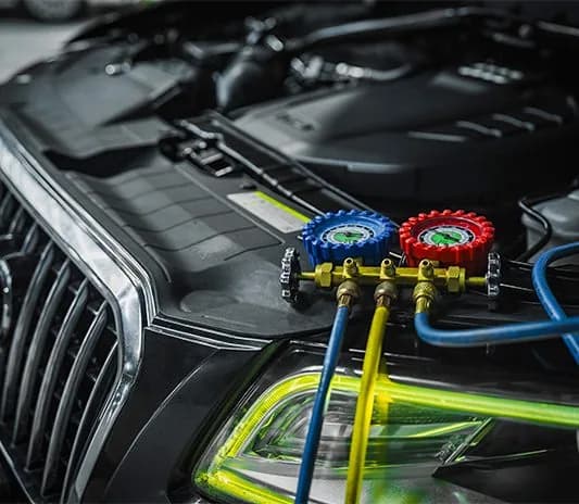 Air conditioning service in progress on an Audi, with pressure gauges connected