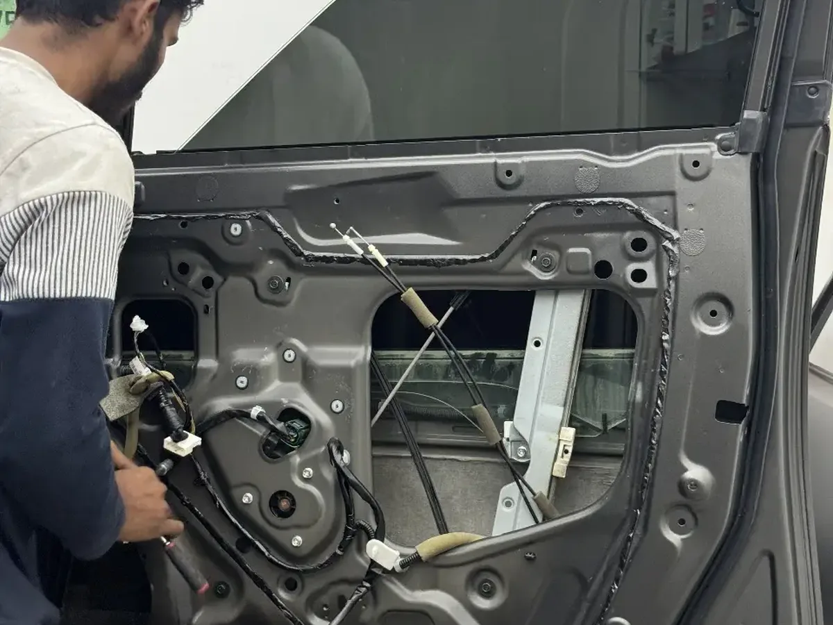 A Zenfo technician working on a door mechanism at the Musaffah workshop